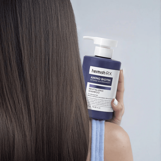 Heimish RX Amino Biotin Revitalizing Shampoo hålls i handen mot långt, glansigt hår – visar resultatet av intensiv näring och återfuktning för torrt hår.