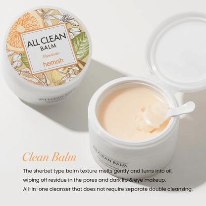 Öppen burk av Heimish All Clean Balm Mandarin med en sked som rör om den krämiga rengöringsbalmen, med en färgglad etikett och texten 'Clean Balm' i förgrunden.
